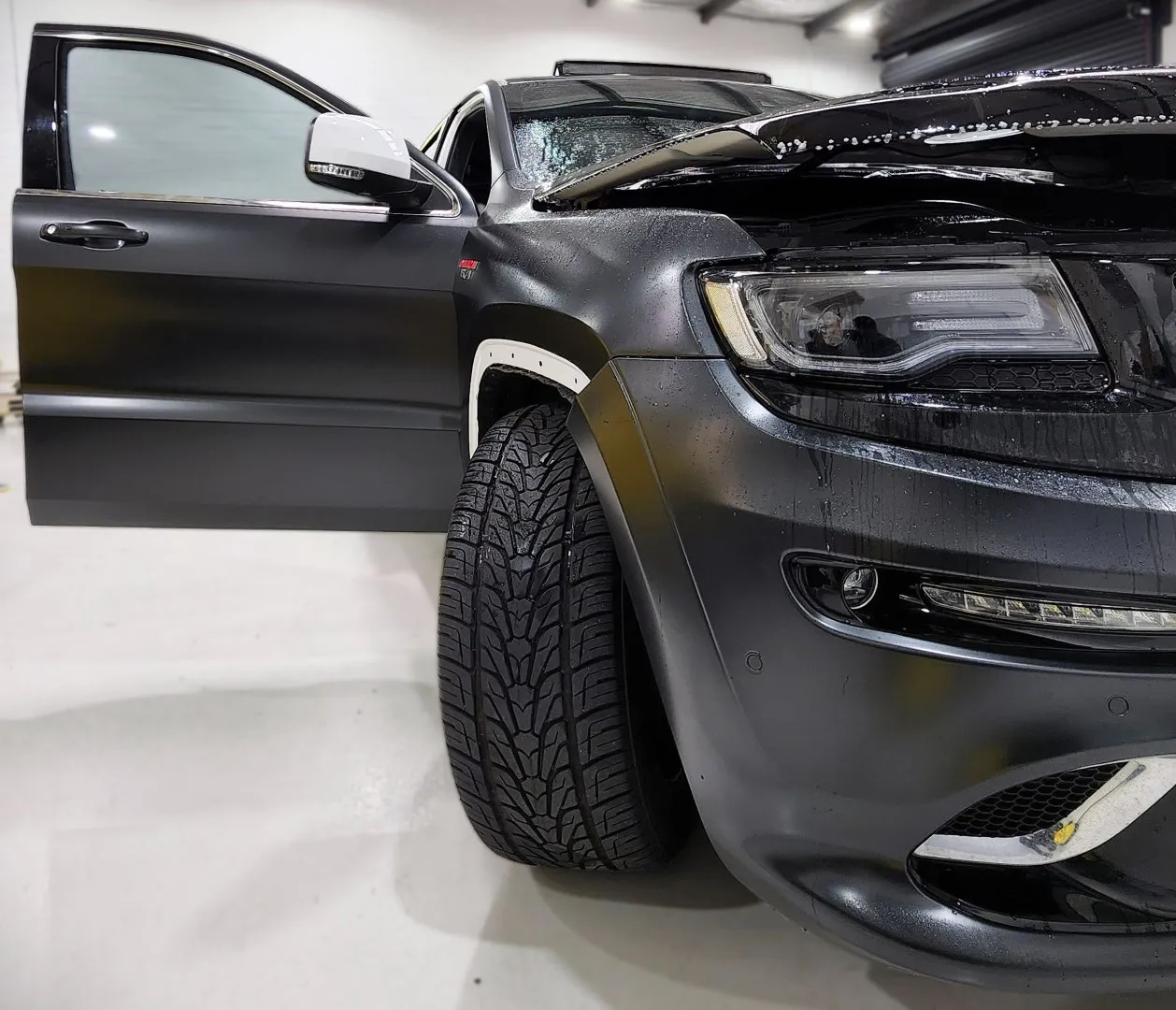 Vinyl wrap edge detail being worked on a Jeep SRT8 panel
